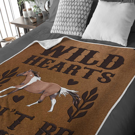 A personalized blanket with the phrase "wild hearts can't be broken" and an image of a running horse placed on a bed, customized as the Ecomartists Custom Wild Hearts Horse Blanket.