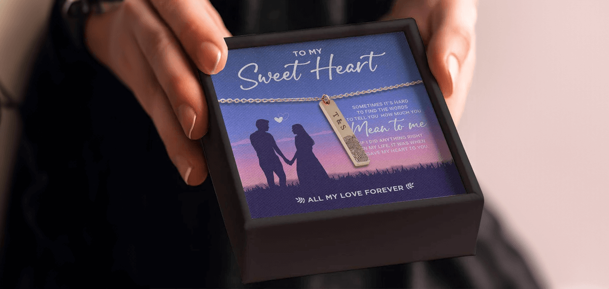 A woman is holding a gift box with a necklace and a picture of a couple.